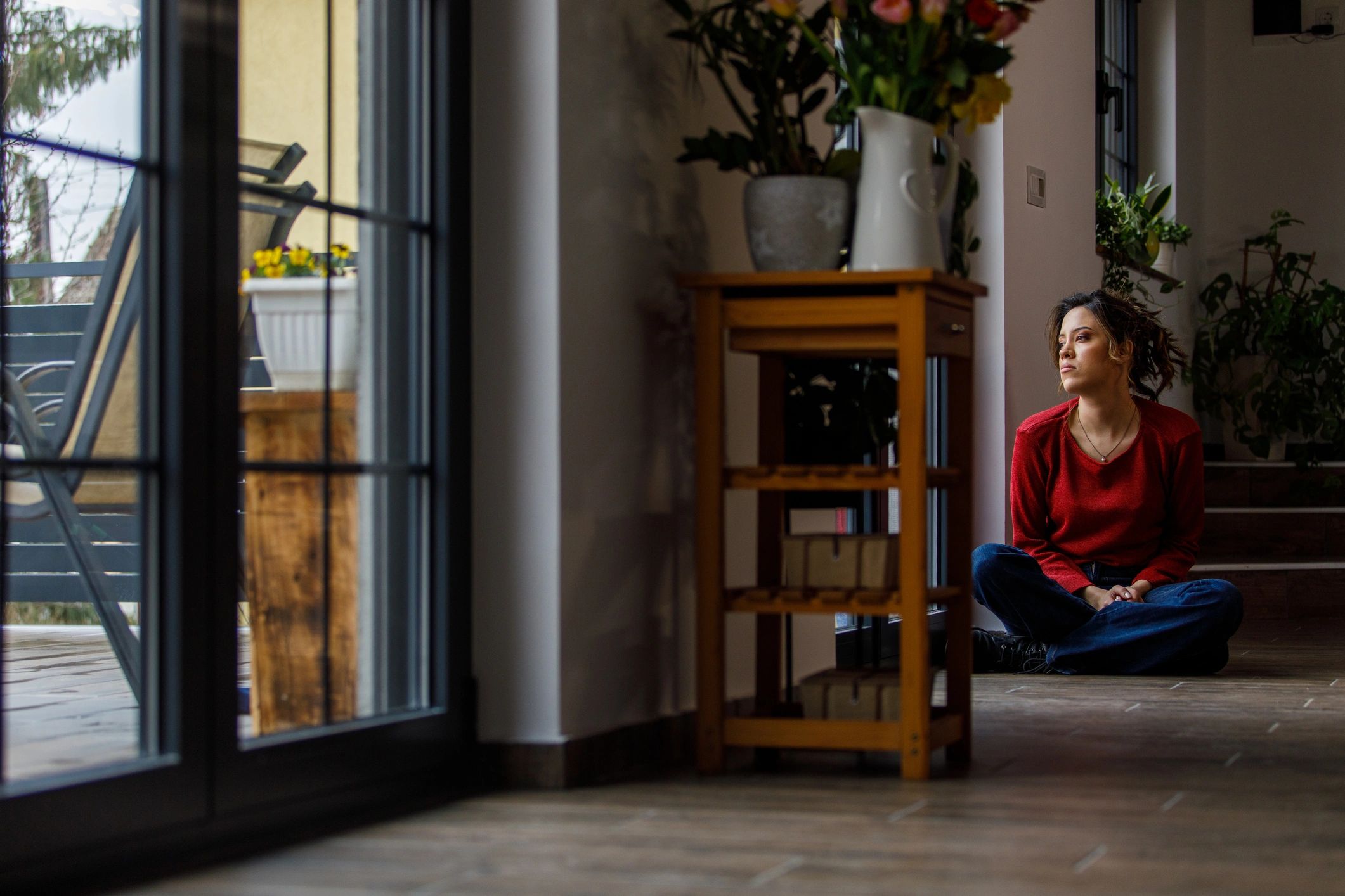 Persona sentada en el suelo junto a una ventana, en una pausa de reflexión
